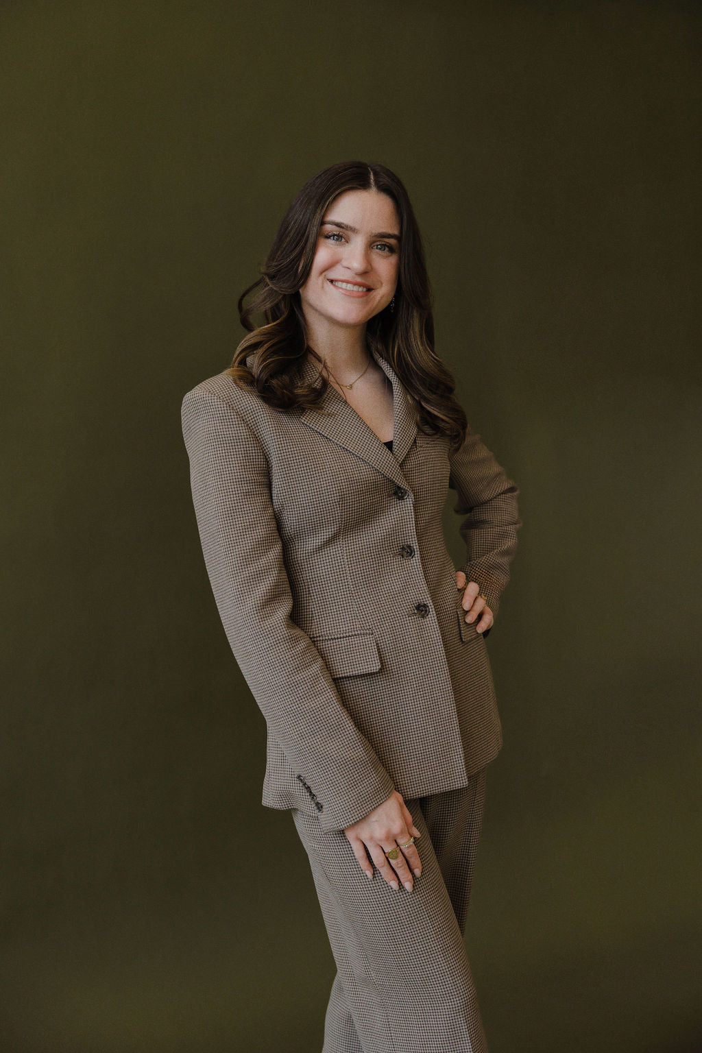 Woman wearing a gingham patterned suit standing against an olive green background