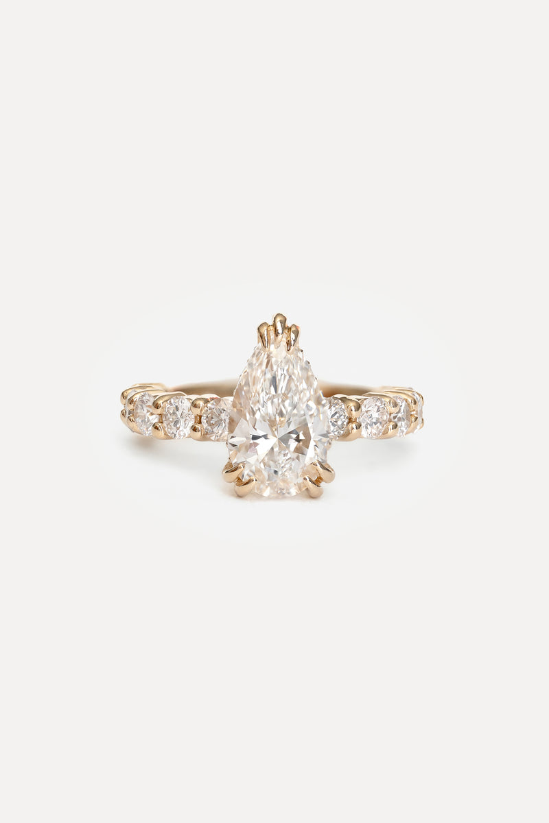 Gold ring with a pear-shaped diamond on a white background