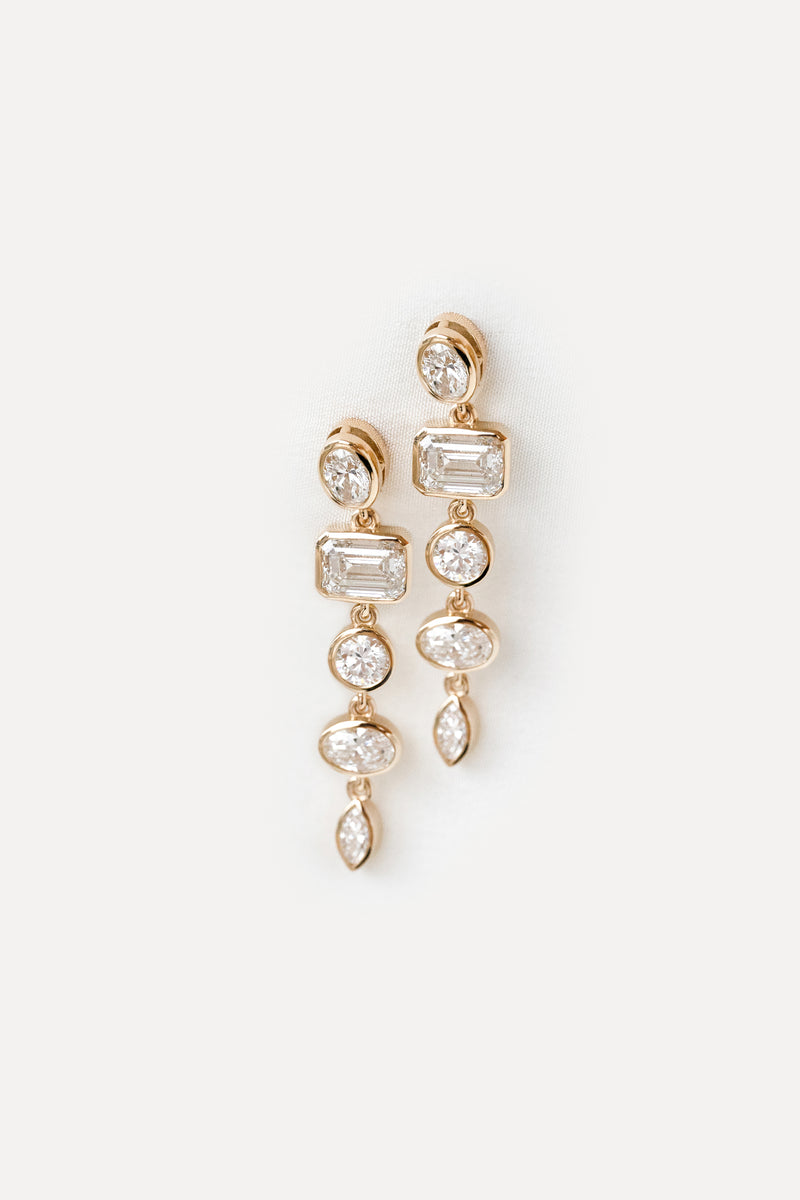 Yellow gold drop earrings with bezel set diamonds in different shapes on a white background