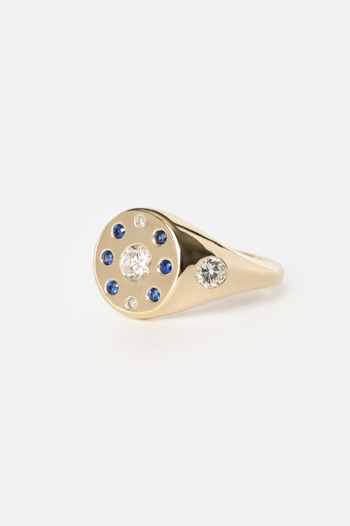 Signet ring with sapphires and diamonds in yellow gold on a white background