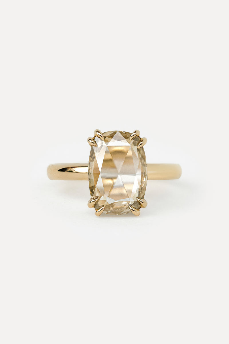 Yellow gold solitaire engagement ring with cushion rosecut diamond set with double claw prongs on a white background