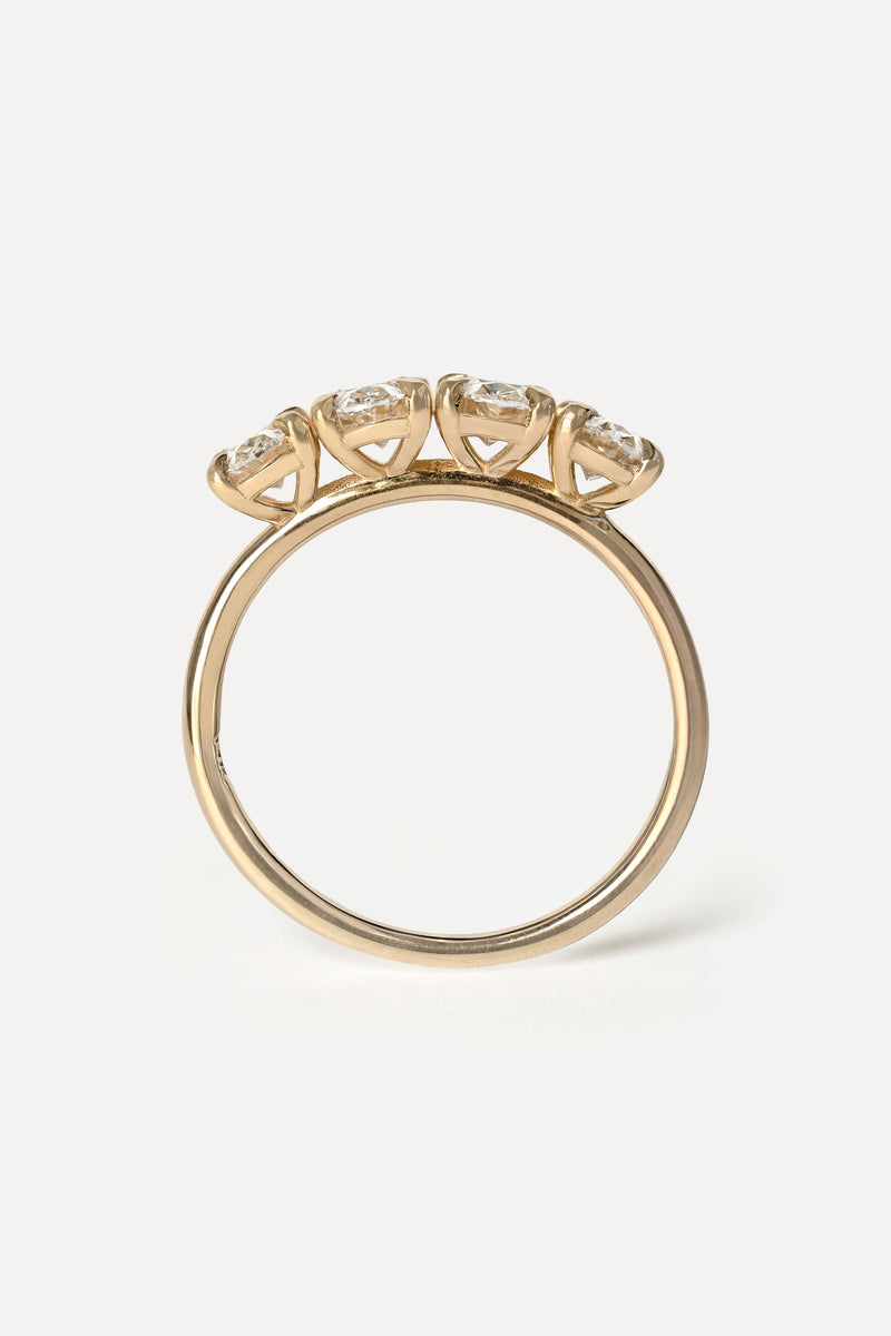 Side profile view of a yellow gold ring with foud diamonds on a white background