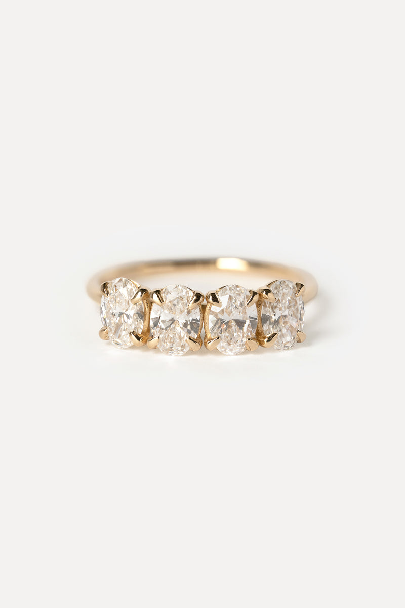 Gold ring with four oval diamonds on a white background