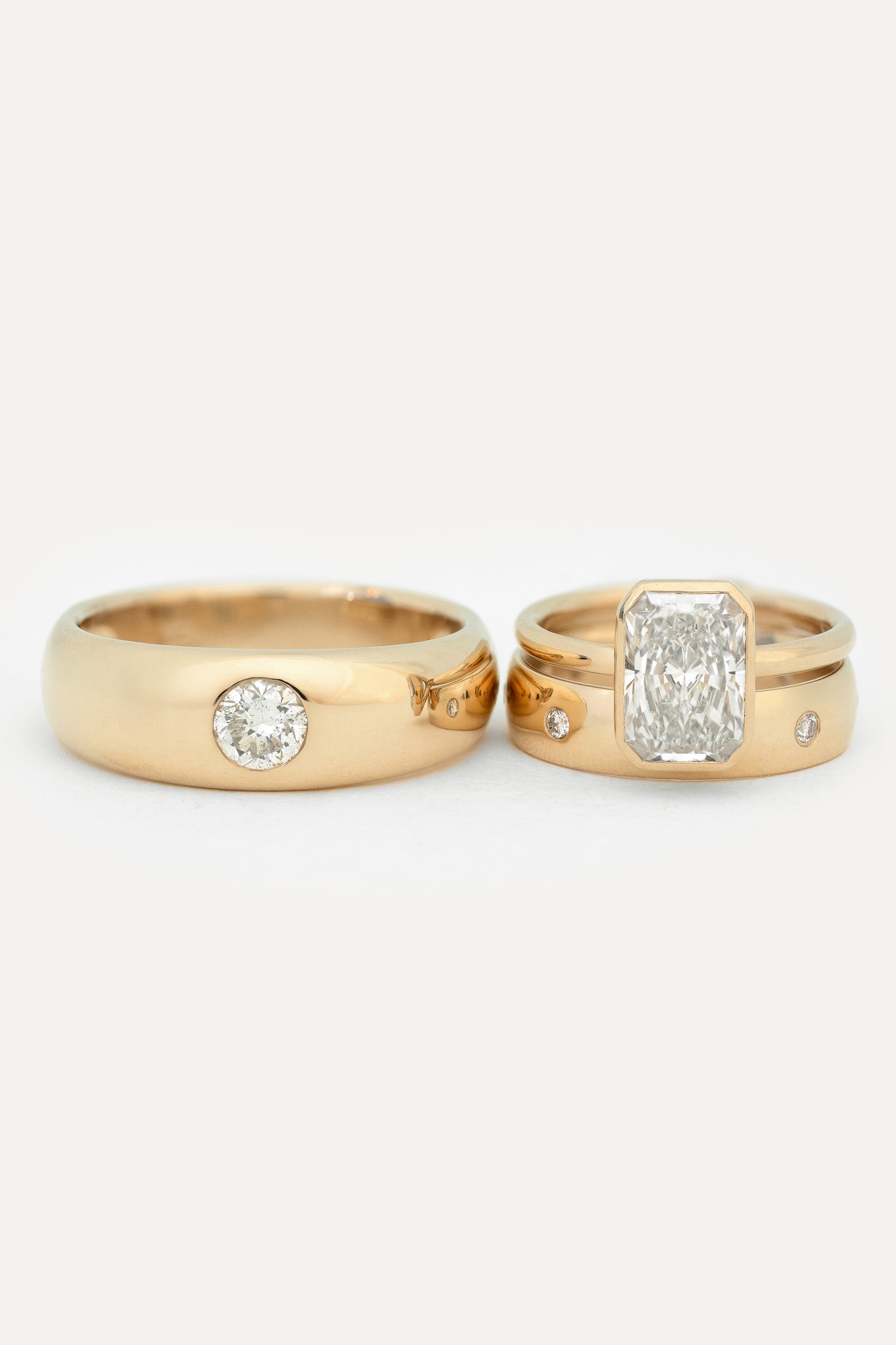 His and hers wedding ring set of two gold bands with round diamonds on a white background