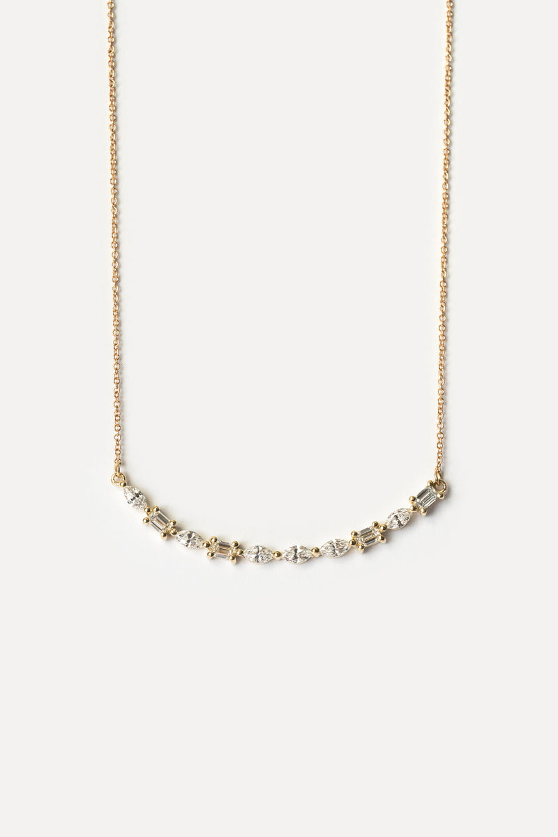 Delicate gold necklace with small gemstones on a white background