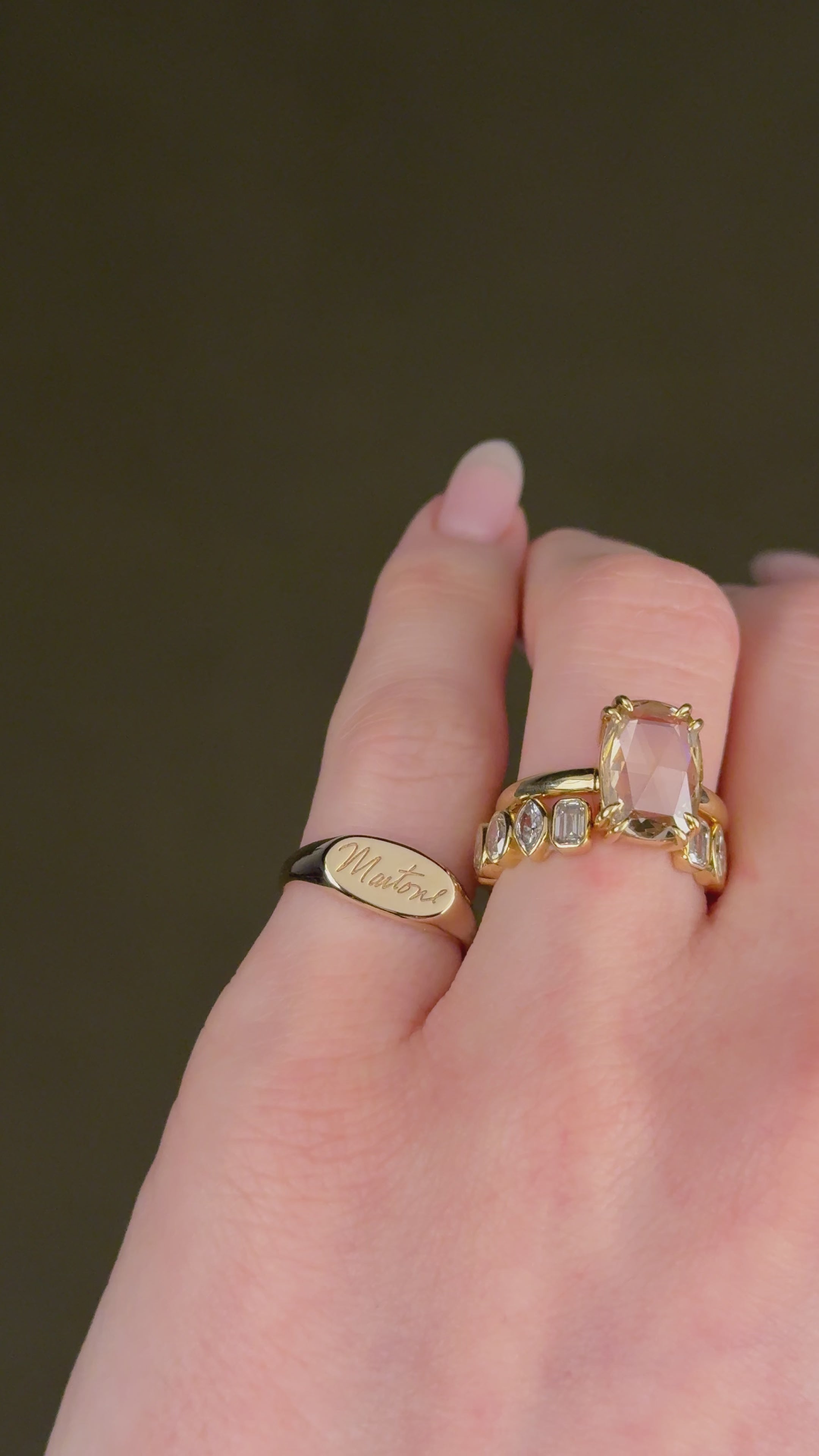 Gold signet ring on the pinky of a women's finger with custom engraved text