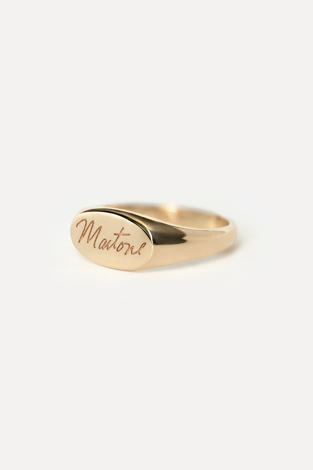 Signet style pink ring with custom handwritten text that spells 'Martone' on a white background