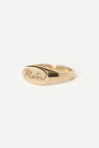 Signet style pink ring with custom handwritten text that spells 'Martone' on a white background