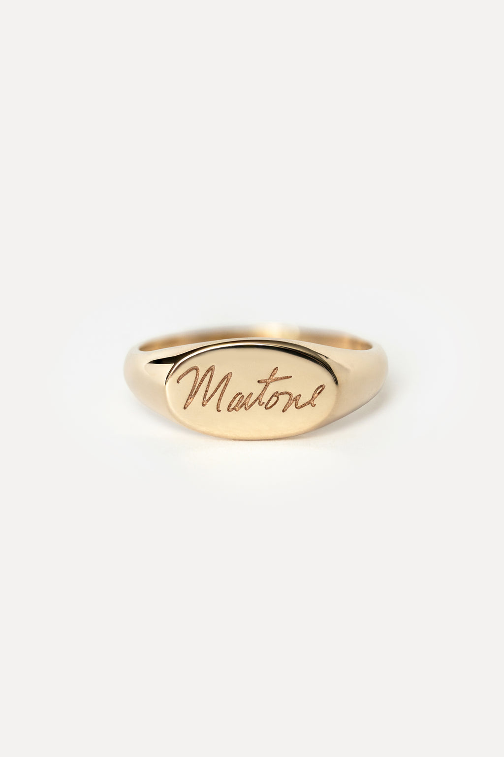 Signet style pink ring with custom handwritten text that spells 'Martone' on a white background