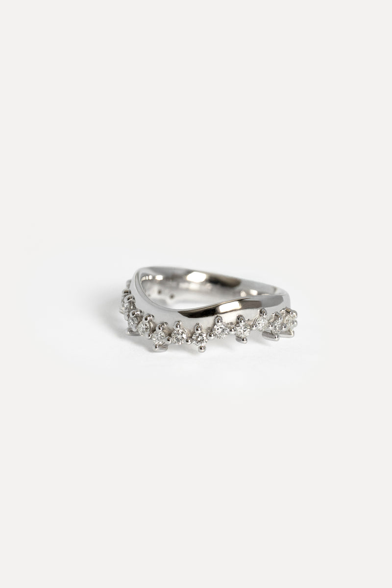 A white gold ring featuring a contour band adorned with small prong set diamonds, photographed on a clean white background.